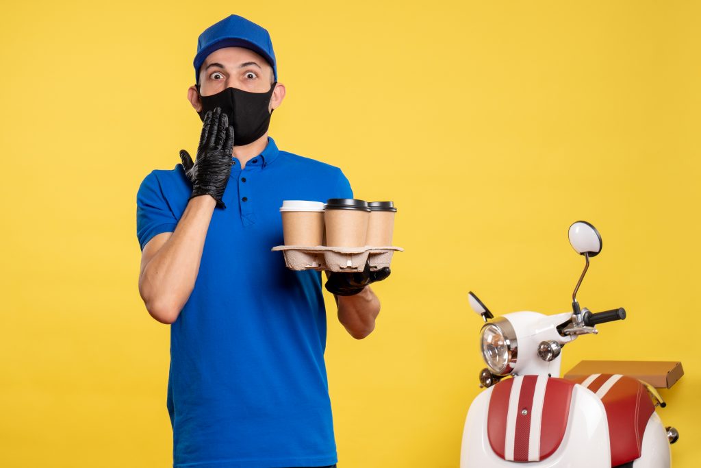 front view male courier black mask holding coffee yellow work delivery job covid pandemic uniform